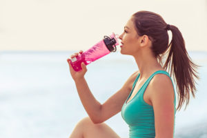 woman drinking water after exercising 