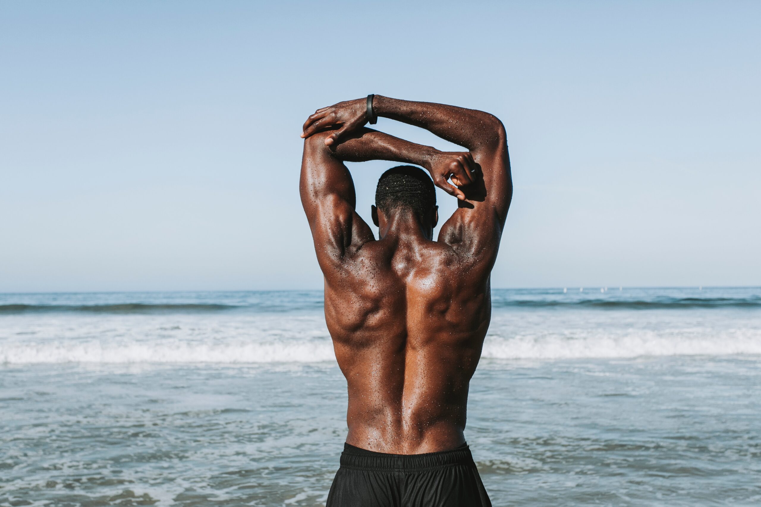 muscle man stretching his arms at the beach before doing exercise&nbsp;