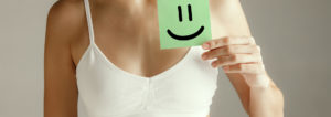 woman holding a piece of paper with happy face emoji written on it